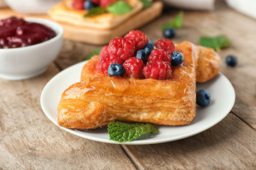 Plate with delicious pastry on wooden table