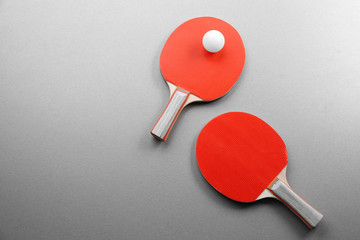 Ping pong rackets and ball on grey background