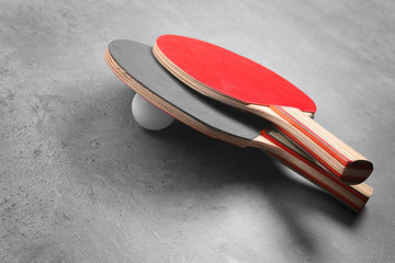 Ping pong rackets and ball on grey background