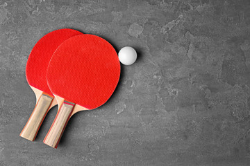 Ping pong rackets and ball on grey background