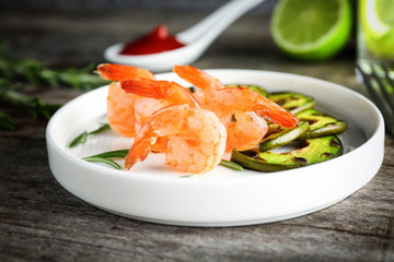 Plate with delicious grilled shrimps on wooden table