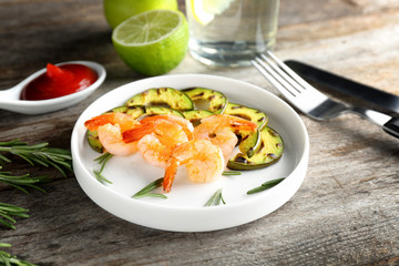 Plate with delicious grilled shrimps on wooden table