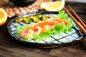 Plate with delicious grilled shrimps on wooden table