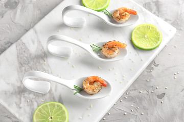 Spoons with delicious grilled shrimps on table