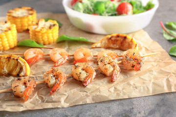 Skewers with delicious grilled shrimps on table