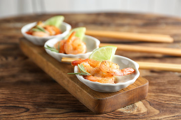Plates with delicious grilled shrimps on wooden table