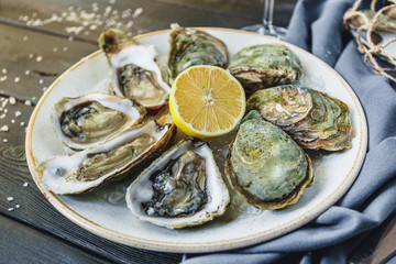 Open wet oysters on a plate with lemon