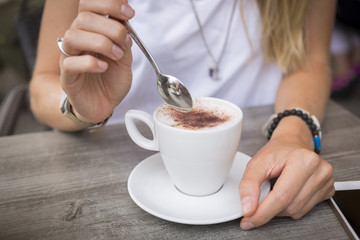 Close-up of woman with cappuccino in a street cafe