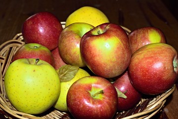Fototapeta na wymiar primo piano di cesto di vimini pieno di mele gialle e rosse