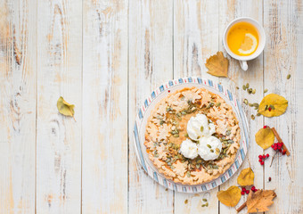 Autumn background with pumpkin pie with ice cream, hot tea, yellowed leaves, book and rug. Perfect sunny autumn. A wooden light white autumn background for you. Copy Space. Flat lay, top view