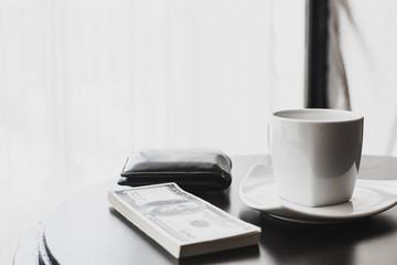Cup of black coffee, newspaper and a pen against the window in the morning