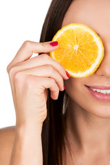 woman covering eye with slice of orange