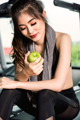 Woman exercise workout in gym fitness holding green apple fruit
