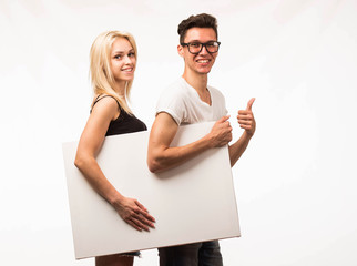 Young [emotion] couple portrait of a confident businessman showing presentation, pointing paper placard gray background. Ideal for banners, presentation, landings, presenting concept.