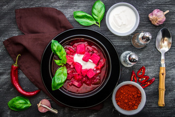 A plate of the national Ukrainian dish on a black wooden background. Borscht