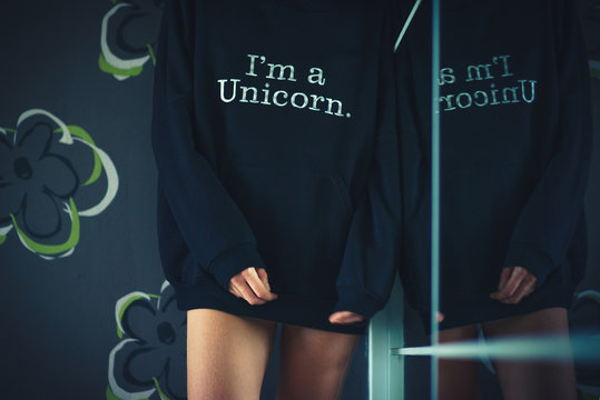 Girl in a stylish hoodie worth about mirrors. Wears a hoodie over his naked body. Portrait without a face. Modern fashion