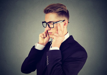 Closeup portrait of a sad young business man with worried stressed face expression looking down  