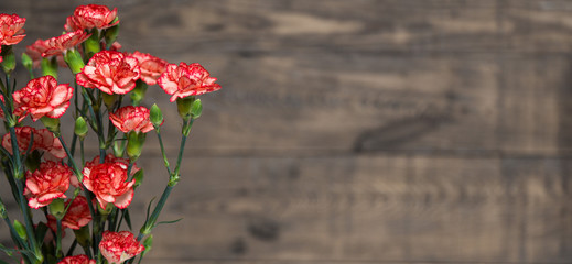 A bunch of red and pink cloves flowers on a rustic wooden table.