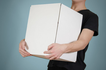 The guy in the black shirt holding a large white box. Carries a box on an isolated blue background.