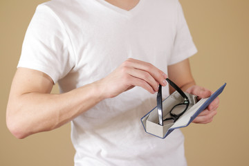 Man in white t shirt hand puts glasses in case with isolated background