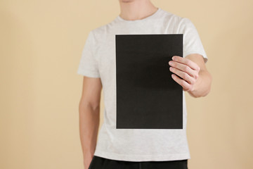 Man holding black A4 paper vertically. Leaflet presentation. Pamphlet hold hands. Man show clear...