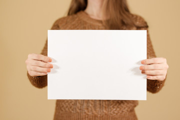 Girl holding white blank paper horizontally. Leaflet presentation. Pamphlet hold hands. Woman show clear offset paper. Sheet template. Booklet design sheet display read first person. Pointing finger.