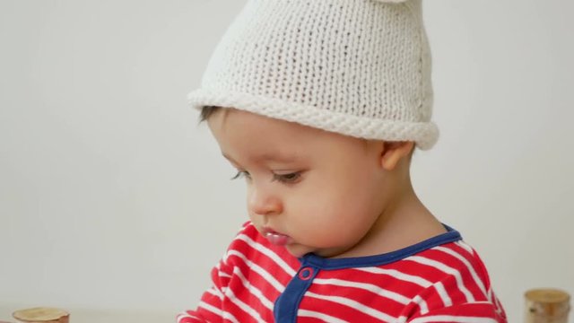 child sits on a small wooden bed in red striped pajamas