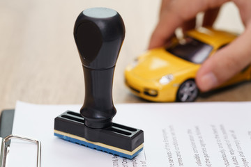 Approved rubber stamp and car model toy with loan application on wooden desk