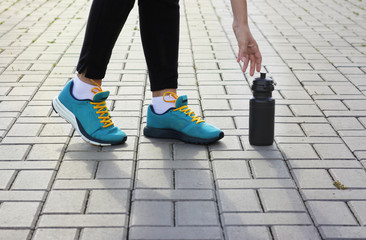 Young girl in sneakers reaching for a bottle
