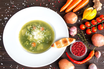 minestrone. vegetable soup in white plate and ingredients on dark wooden rustic table. top view