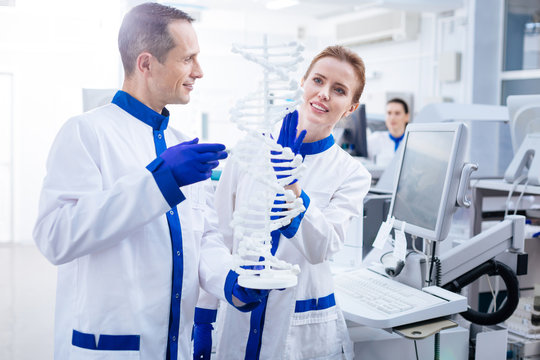 Molecule organization. Happy glad male and female team of scientist examining molecules in DNA and smiling while posing in the lab