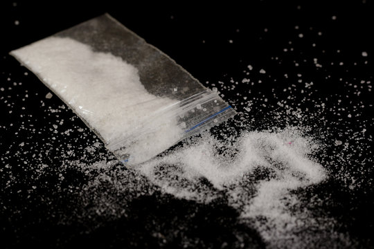 Cocaine in the bag, scattered. Isolated on a black background.