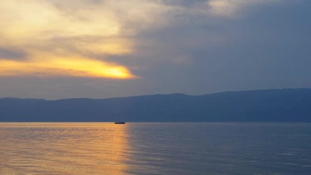 Beautiful sunset. Oppositions of red and blue. The sky is divided in half. A smooth line runs along the sea. The sun is behind the clouds.