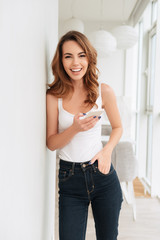 Amazing smiling young lady standing near window chatting