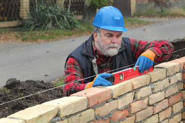 Worker examining brick wall using level tool