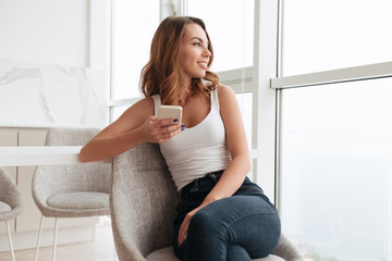 Smiling young woman sitting near window chatting