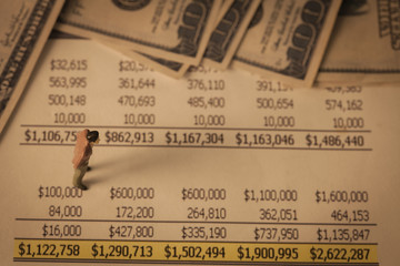 Miniature business man on income report and bank