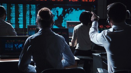 Financial traders working in modern office analyzing statistics and driving trade on exchange.