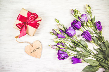 Purple flowers and box with a gift on a white background. Celebratory concept.
