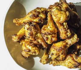 Grilled chicken drumsticks fried crispy marinated with honey is served in a flat white dish on a white background , Asian flavors and style, close-up