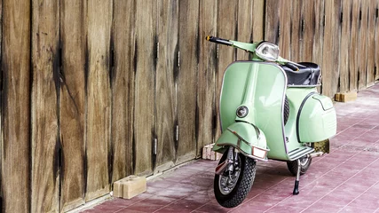 Foto op Plexiglas Scooter Groene scooter tegen oud huis. houten muur bemoste oppervlak van gebouw als achtergrond. Stedelijke straat in Thailand, Azië. Bromfiets geparkeerd op beschimmelde houten muur. Aziatische levensstijl en populair vervoer.