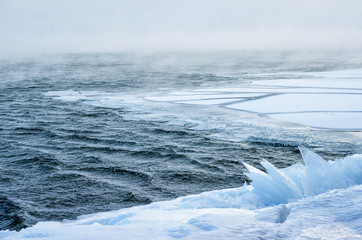Ice floes floating on the fog water in the lake Baikal. Sunset