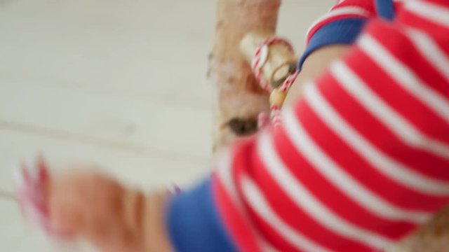 child sits on a small wooden bed in red striped pajamas