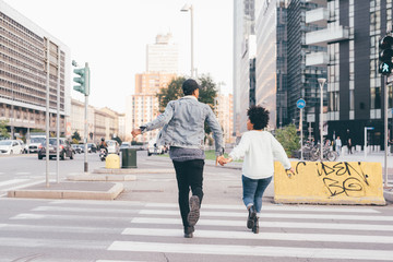 Obraz premium Back view of young multiethnic couple running outdoor in the city holding hands, having fun - happiness, friendship, lovers concept