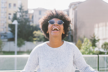 Portrait of young beautiful afro woman outdoor in the city back light having fun - carefree, serene, thoughtless concept