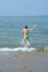Fototapeta na wymiar Mädchen im grünem Bikini rennt ins Meer