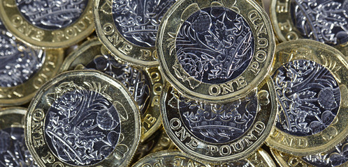 Full frame of a heap of British one pound coins in a panoramic format