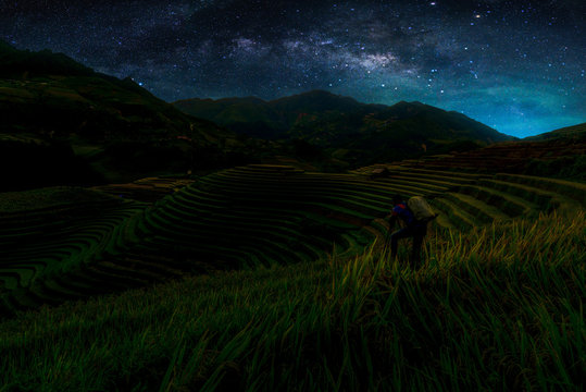Landscape with Milky way galaxy. Night sky with stars and silhouette Photographer take photo over Rice fields on terraced in Mu Cang Chai. Long exposure photograph.