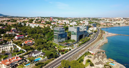 Obraz premium Aerial Fly Over People Crowd Having Fun On Beach And Over Cascais City In Portugal