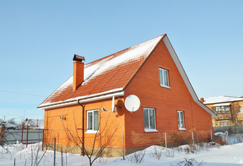 Brick House with  red metal roof tile and chimney covered snow in winter outdoor